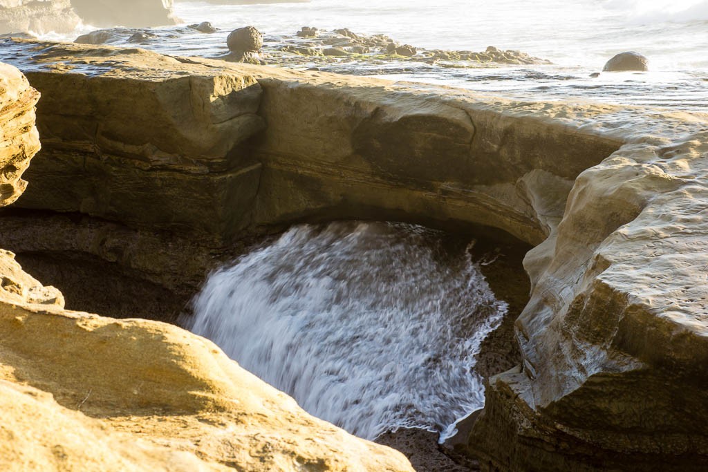 Waves gushing through a hidden rock bridge