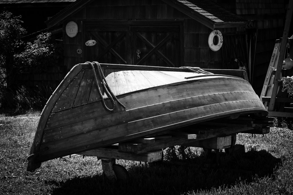 Wooden rowboat next to a matching wooden barn